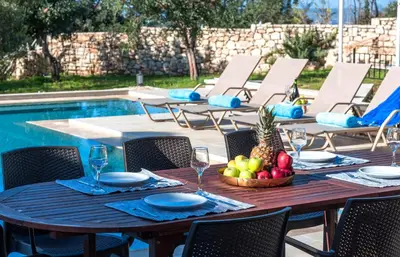 a table with a bowl of fruit next to a pool at Cretan Lux Villa Heated Pool in Gavalochori