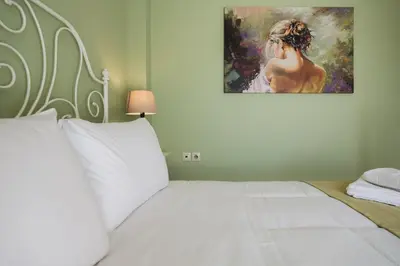 a bedroom with a white bed with a painting on the wall at Ar & Al Luxury Villa in Galatás