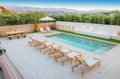 a patio with chairs and a pool with a table at Ar & Al Luxury Villa in Galatás