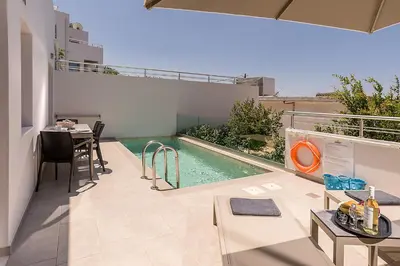 a swimming pool in the middle of a patio with a table at Sunset Elafonisi Apartments in Livadia