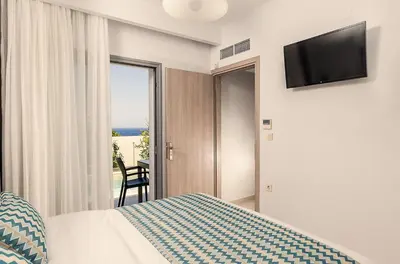 a bedroom with a bed and a tv and a window at Sunset Elafonisi Apartments in Livadia