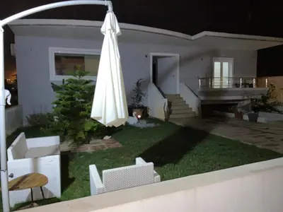 a yard with an umbrella and chairs and a house at Stellina's new studio 5min from beach in Souda