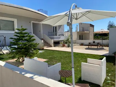 a patio with an umbrella and a table and chairs at Stellina's new studio 5min from beach in Souda