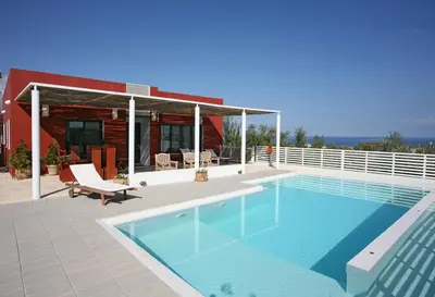 a swimming pool in front of a house at Villa Bamboo in Maleme