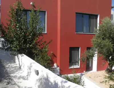 a red building with trees in front of it at Villa Bamboo in Maleme