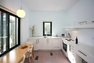 a kitchen with white cabinets and a wooden table at Villa Bamboo in Maleme