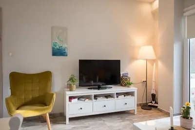 a living room with a television and a chair at The Prickly Pear Apartment in Chania Town