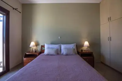 a bedroom with a large bed with purple sheets and two lamps at Terpsis House in Kissamos