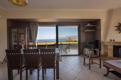 a living room with a table and a view of the ocean at Terpsis House in Kissamos
