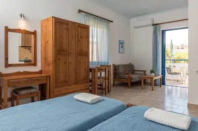a bedroom with two beds and a desk and a mirror at Anthea Apartments in Palaiochóra