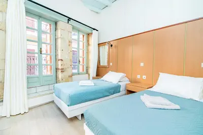 two beds in a room with two windows at Alegria Pension in Chania Town