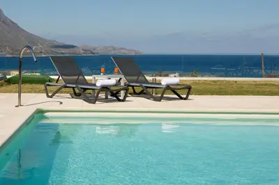 two chairs and a table next to a swimming pool at Larimar Luxury Sea View Villa in Kissamos