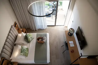 a room with a bed with pillows and a television at Mossa Well Being Hotel - Heated pool and Wellness Spa in Kato Daratso