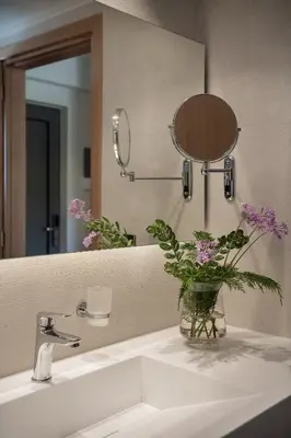 a bathroom sink with a mirror and a vase with flowers at Mossa Well Being Hotel - Heated pool and Wellness Spa in Kato Daratso