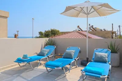 a group of blue chairs and an umbrella on a patio at Celestine Suites in Kolymvari