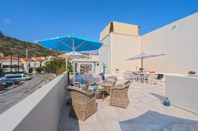 a patio with chairs and a table with an umbrella at Celestine Suites in Kolymvari