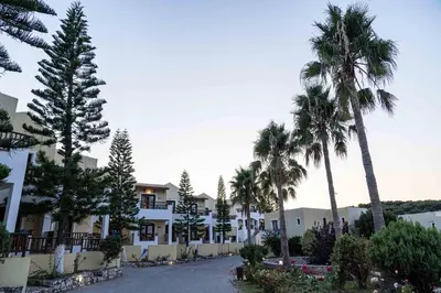 a street in front of a building with palm trees at Almyrida Village & Waterpark in Almirida