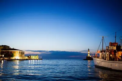 a boat is docked in the water at night at Koum Kapi Boutique Apartments in Chania Town