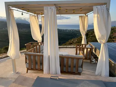 a gazebo with white curtains and chairs on a roof at Ellas Residence fantastic pool heated in Kissamos