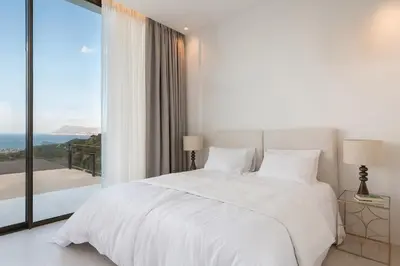 a white bedroom with a bed and a large window at Ellas Residence fantastic pool heated in Kissamos