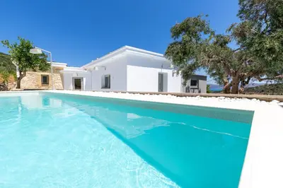a swimming pool in front of a white house at Villa Evrithea in Kalleryianá