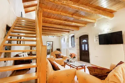 a living room with a wooden staircase and a couch at Traditional Stone House Rafael in Tzitzifés