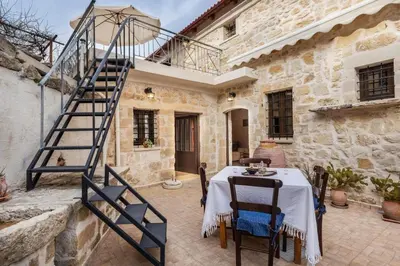 a stone house with a table and a spiral staircase at Traditional Stone House Rafael in Tzitzifés