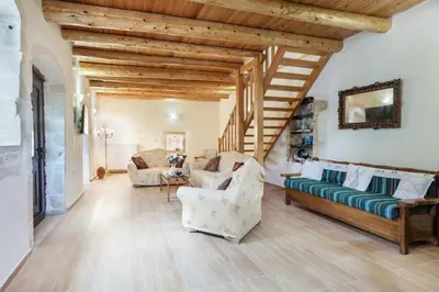 a living room with wooden ceilings and a staircase at Traditional Stone House Rafael in Tzitzifés
