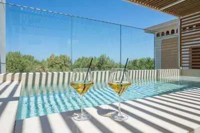 two glasses of wine sitting on a table next to a swimming pool at SanSal Boutique Hotel in Chania Town