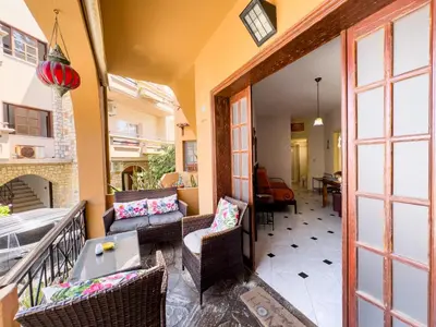 a porch with chairs and a table and a fireplace at Villa Eleni Seaside Apartments in Plataniás