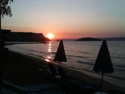 a sunset on the beach with chairs and umbrellas at Lion-Suites in Kalyves