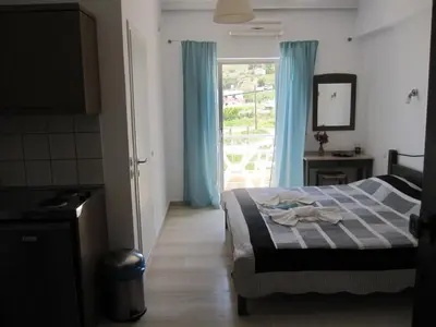 a bedroom with a bed and a window with blue curtains at Lion-Suites in Kalyves