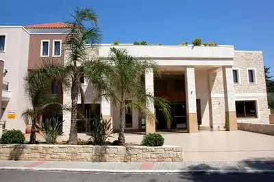 a building with palm trees in front of it at Okeanis Golden Resort in Kato Daratso