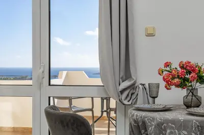 a dining room with a table and a view of the ocean at Panoramio Paleochora Apartments in Palaiochóra