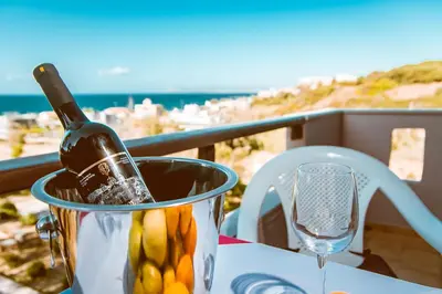 a bottle of wine in a bucket on a table with a glass at Gregory Village Sea View in Stalos