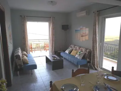 a living room with a blue couch and a balcony at Riza Falasarna Apartments in Falasarna
