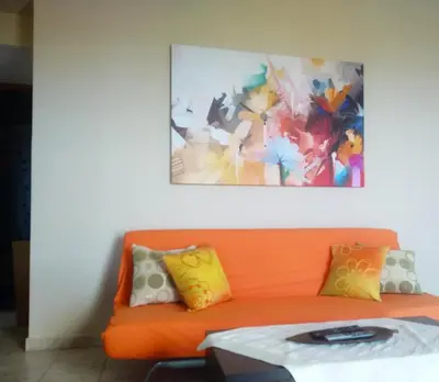 an orange couch with pillows and a painting on the wall at Riza Falasarna Apartments in Falasarna