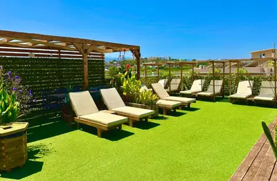 a row of chaise lounge chairs on a lawn at Pearl Seaside Cozy Apartments in Chania Town