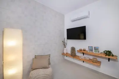 a living room with a couch and a tv on a wall at Elenas Village house - Dream apt w Pool & Terrace in Alikianós