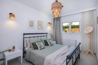 a bedroom with a bed and a table and windows at Elenas Village house - Dream apt w Pool & Terrace in Alikianós