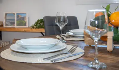 a wooden table with plates and wine glasses on it at Elenas Home - Dream & Love apts w Private pool in Alikianós