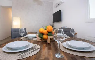 a dining room table with plates and glasses and a bowl of oranges at Elenas Home - Dream & Love apts w Private pool in Alikianós