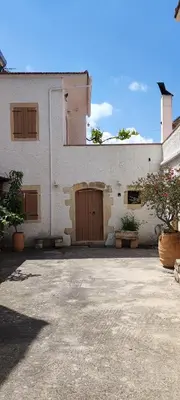 a white building with two brown doors on it at Irene's Guest House in Frés