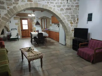 a kitchen and a living room with a table and a couch at Irene's Guest House in Frés
