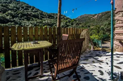 a wooden chair and table on a patio with a fence at Spitia Katoi in Palaiochóra