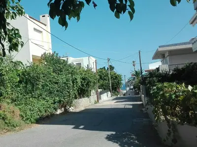 an empty street with buildings and trees on the side at New Sea Escape Boutique Apt-Agii Aposto li beach in Chania Town