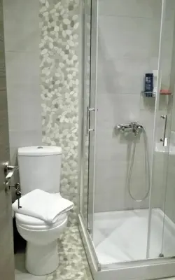 a bathroom with a toilet and a glass shower at New Sea Escape Boutique Apt-Agii Aposto li beach in Chania Town