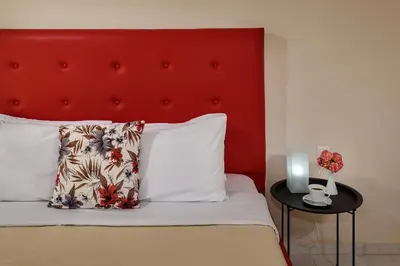 a bed with a red headboard and a table with a pillow at Room 25 in Chania Town