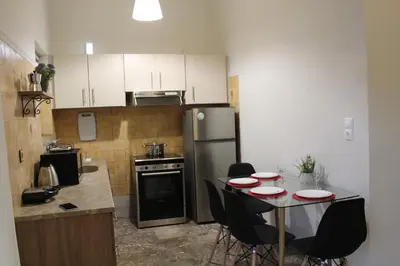 a small kitchen with a table and a refrigerator at Chania Nice Apartment in Chania Town