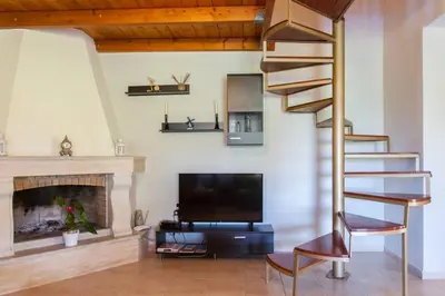 a living room with a spiral staircase and a fireplace at Kaktos 1 in Kissamos